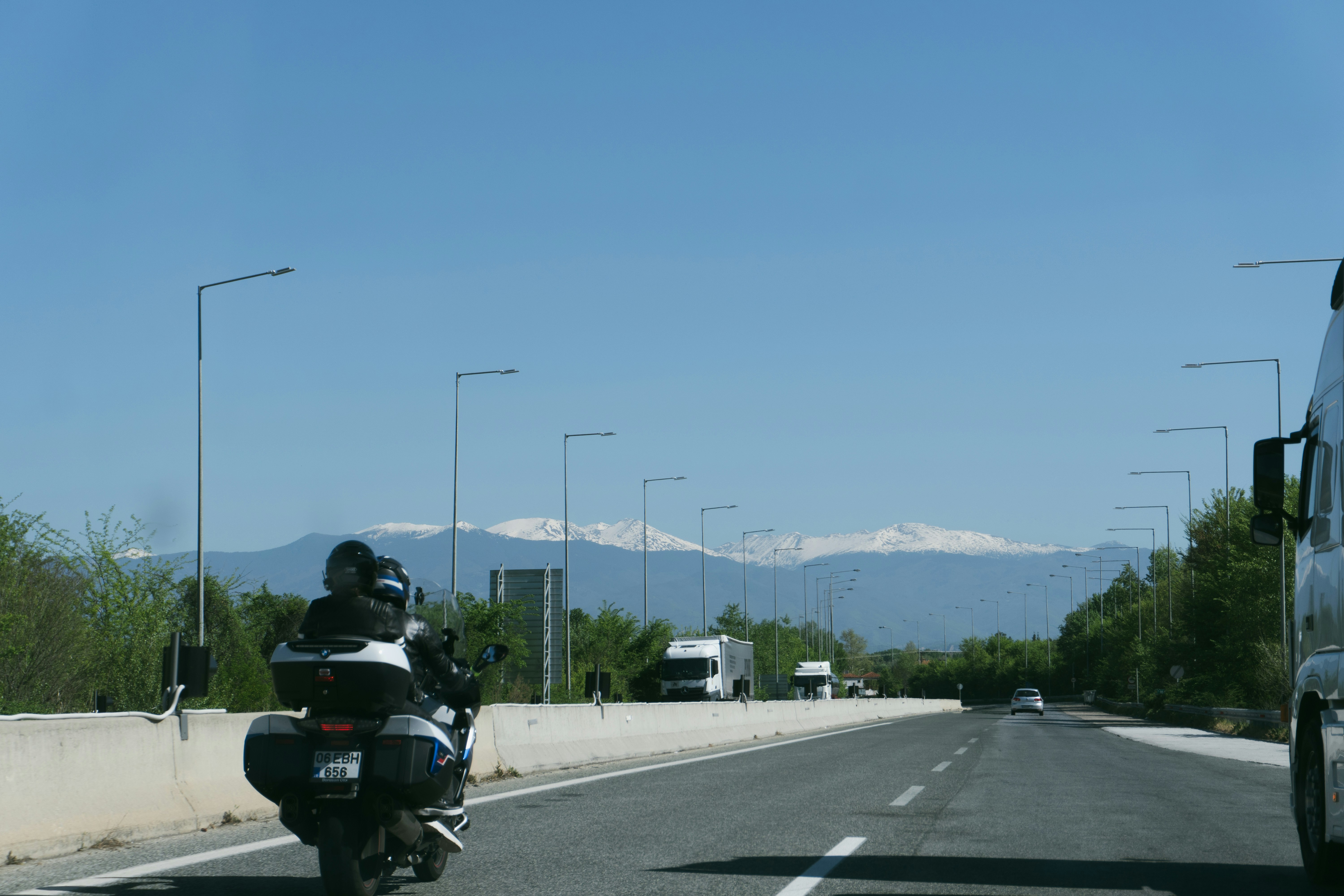 a motorcyclist riding down a highway with mountains in the background