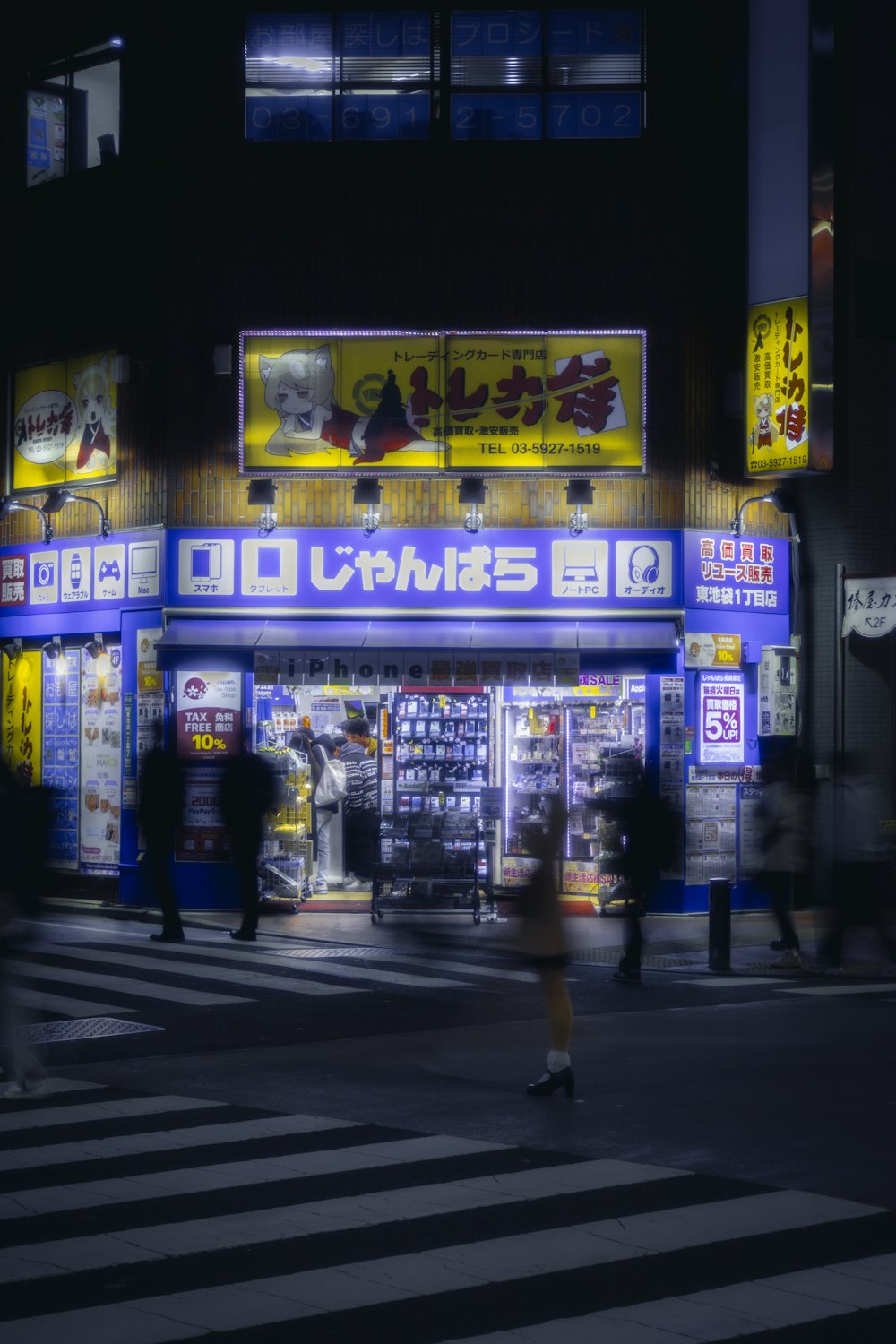 a city street at night with people crossing the street