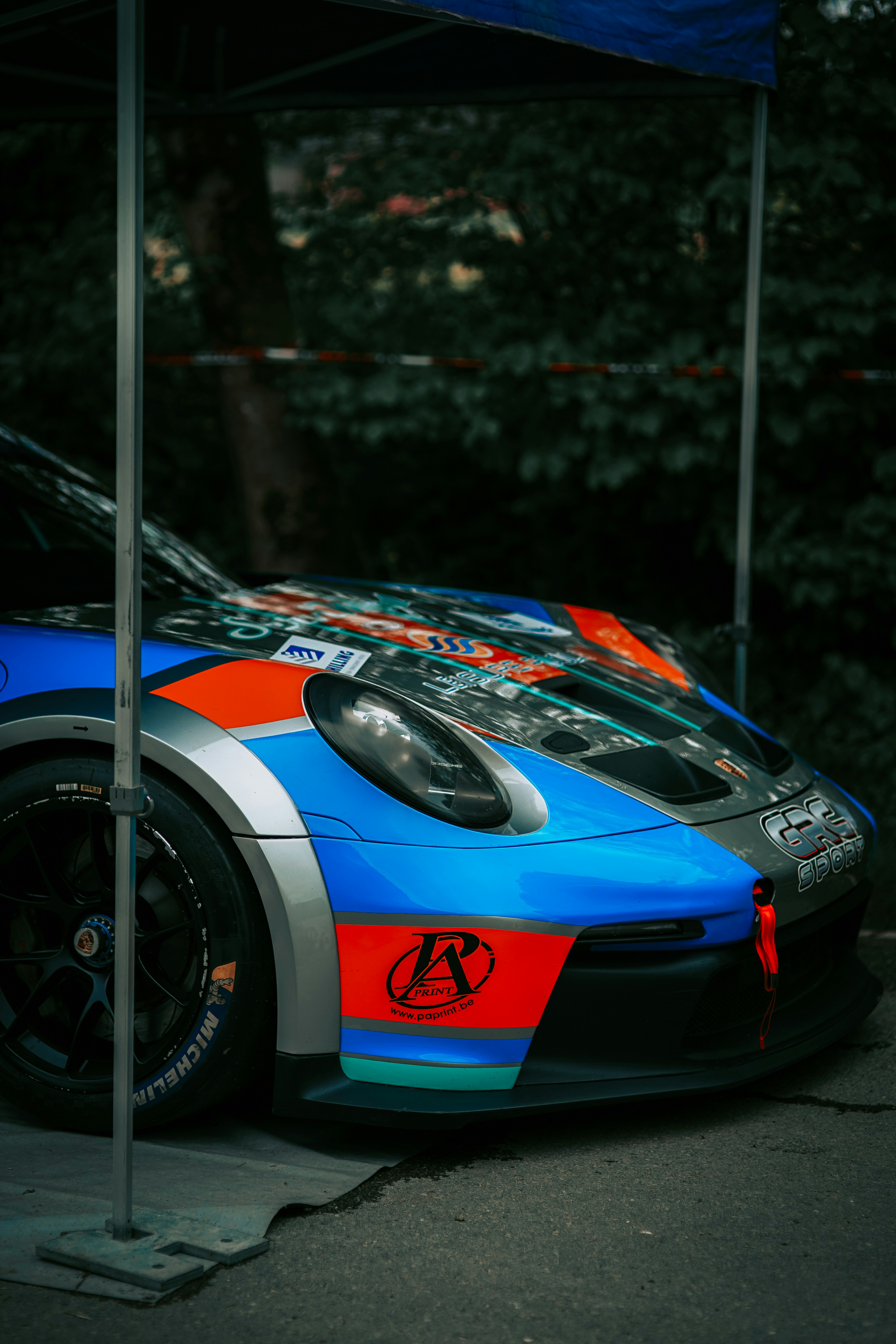 a blue and orange car parked under a tent