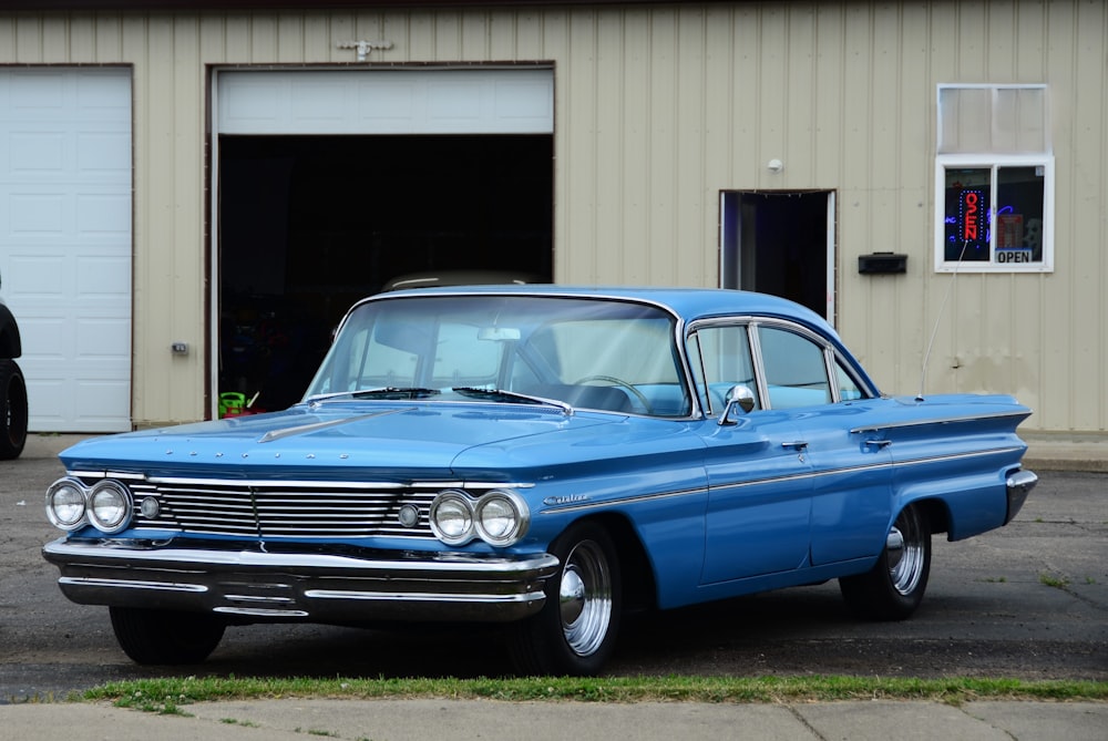 a blue car parked in front of a garage