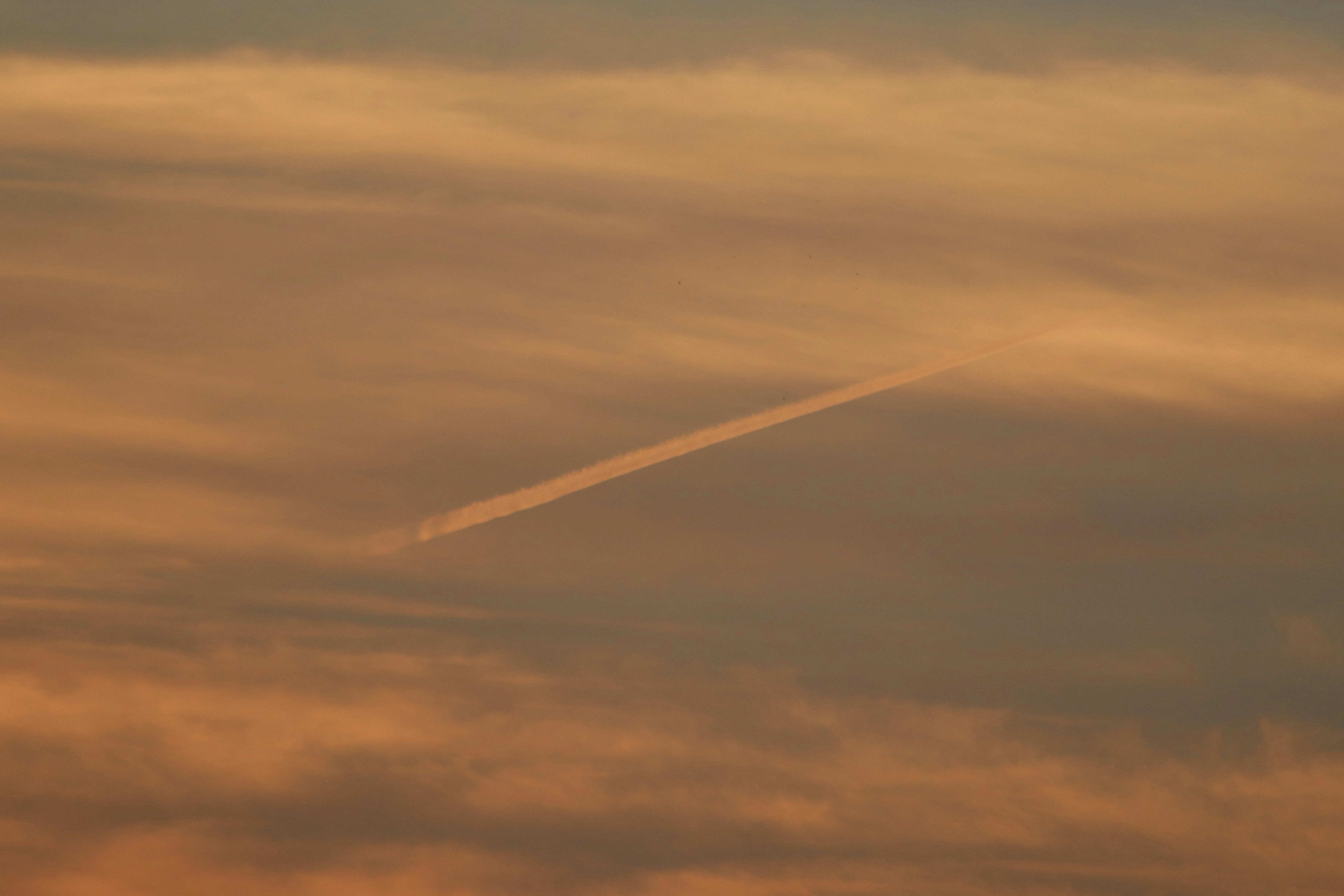 a plane flying in the sky with a contrail in the sky