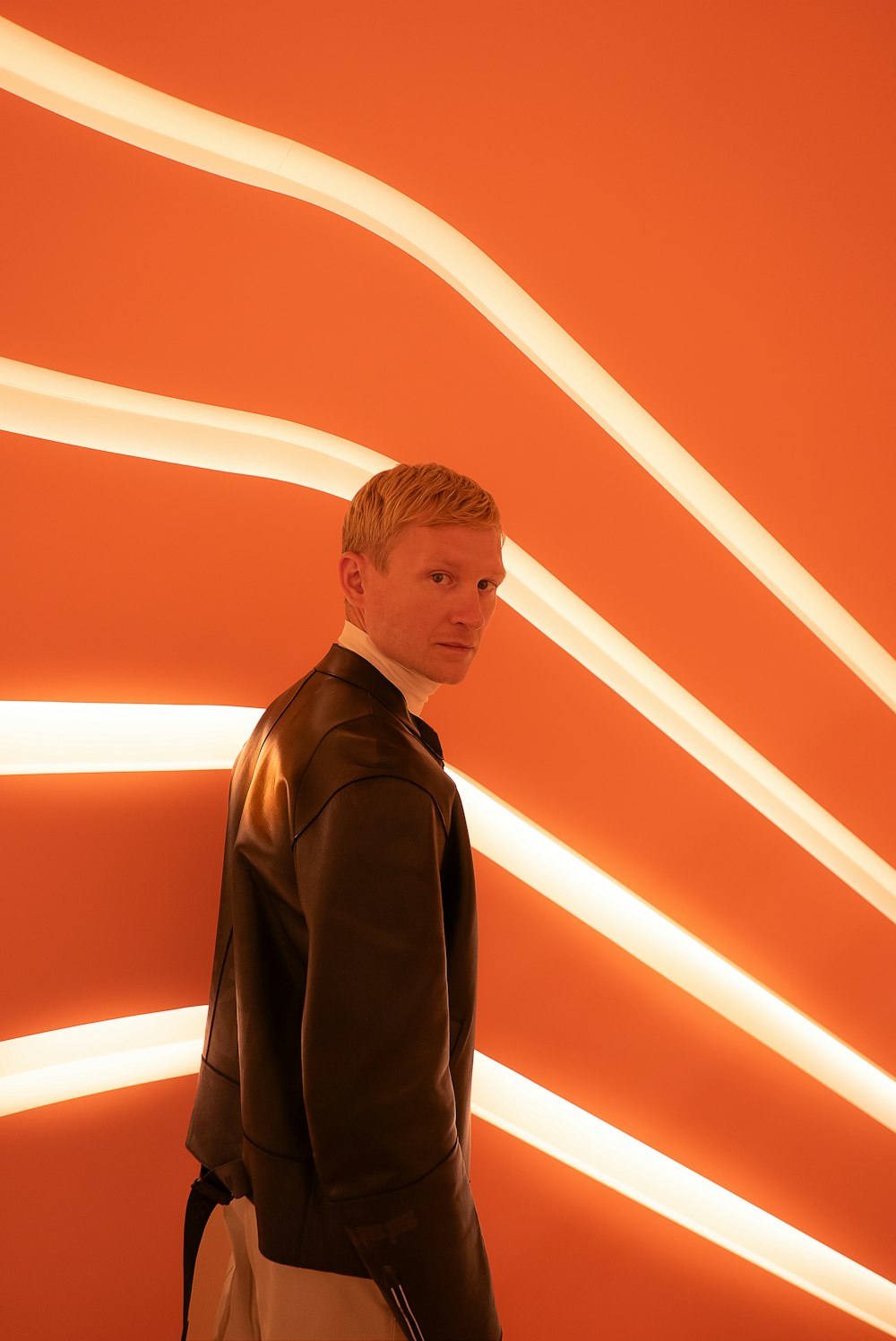 a man standing in front of an orange wall