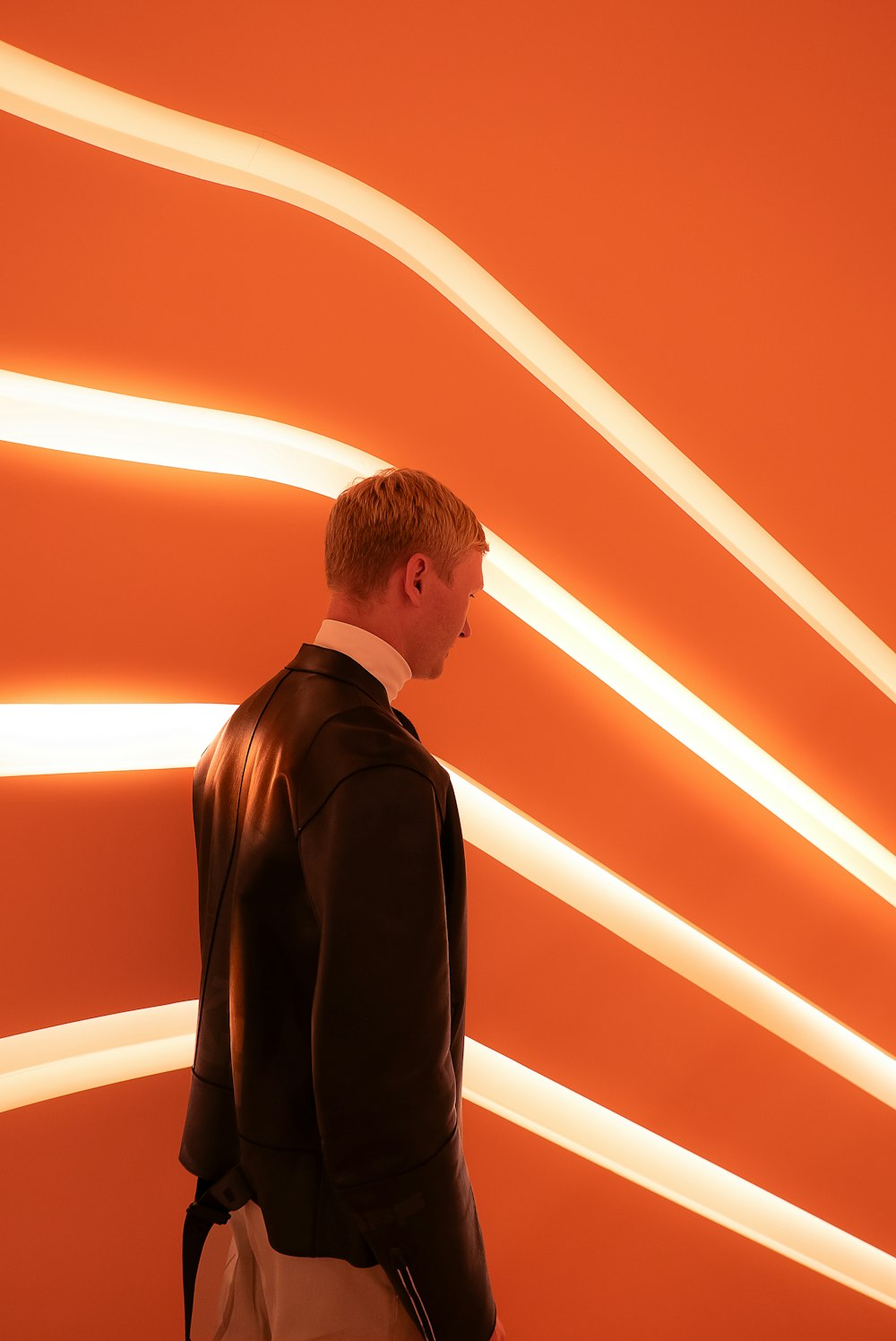 a man standing in front of an orange wall