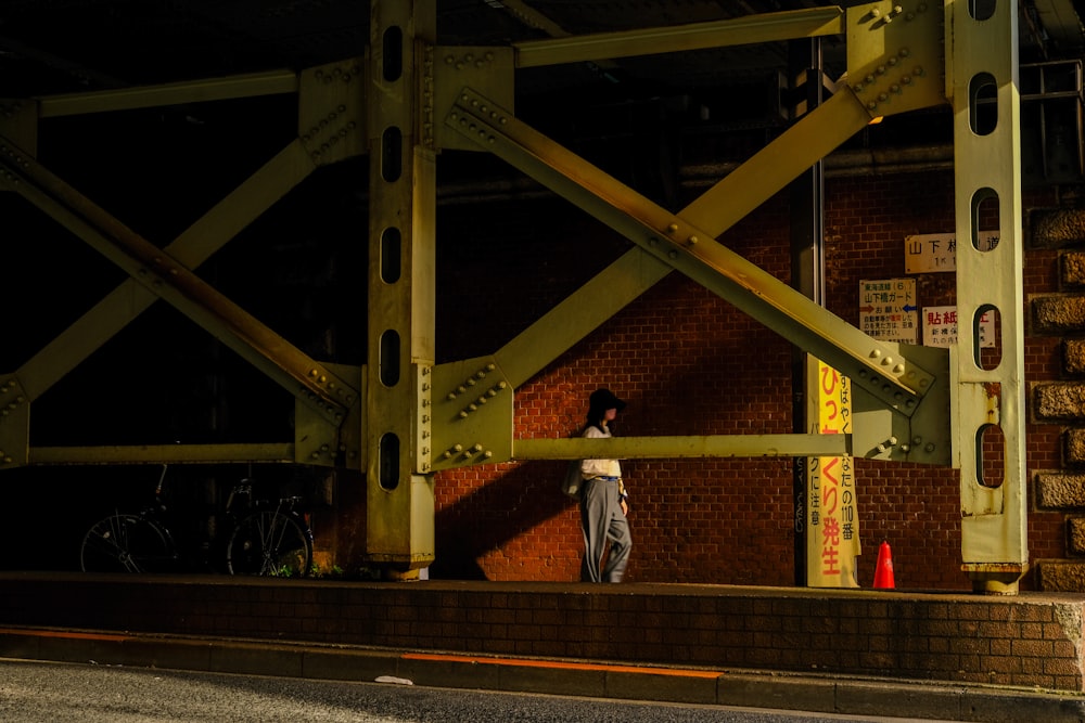 a man standing on a bridge next to a brick wall