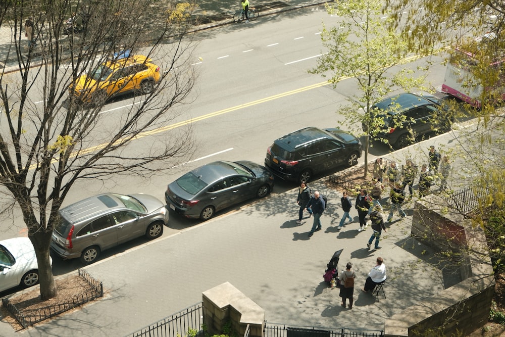 a group of people walking down a street next to parked cars