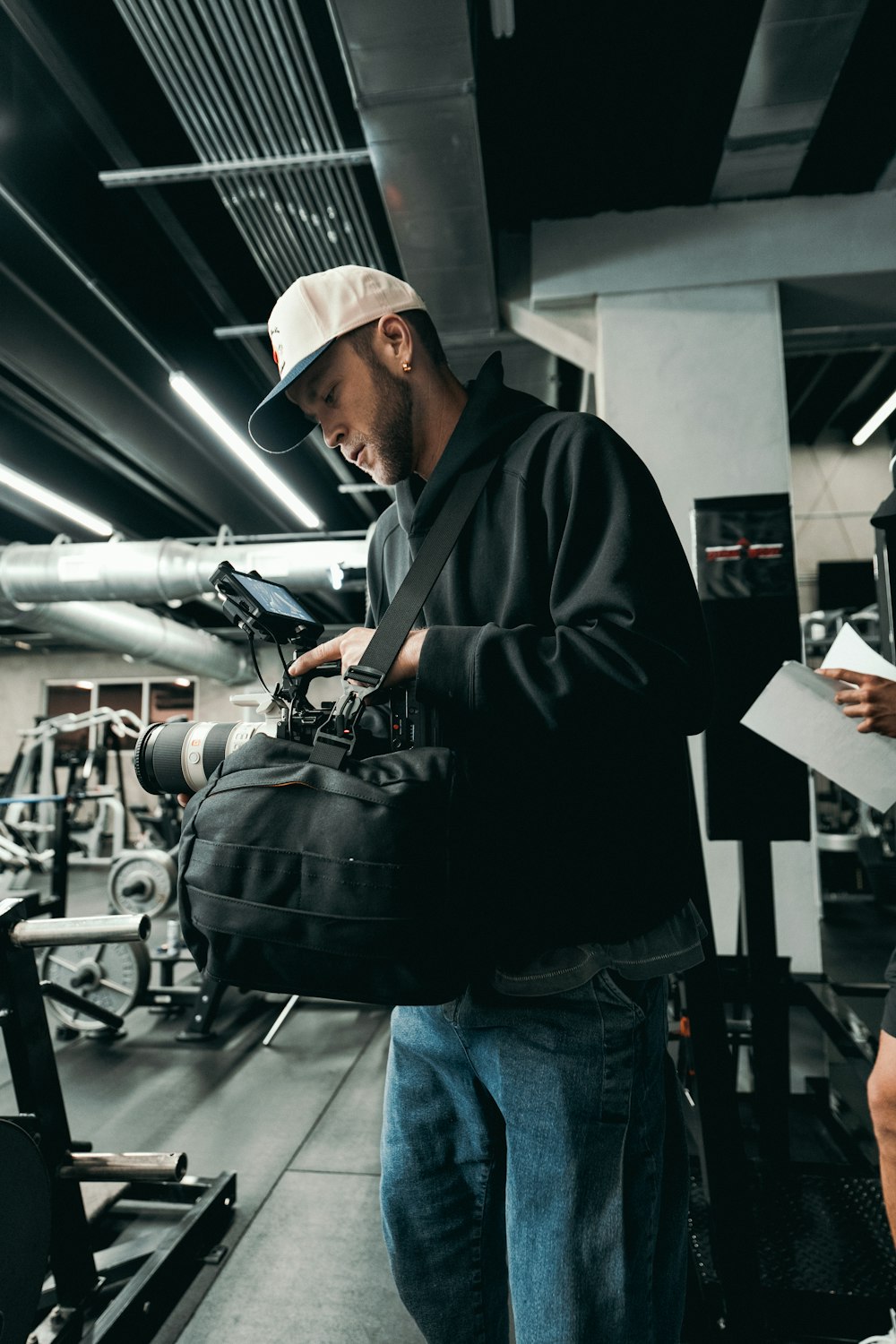 a man standing in a gym holding a camera