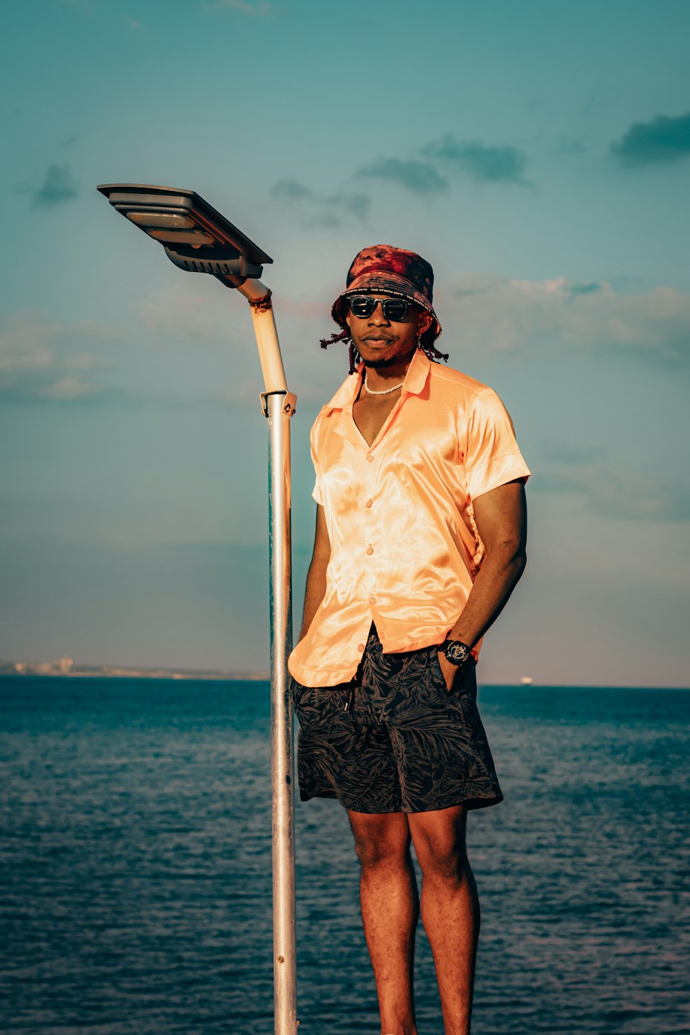 a man standing next to a street light near the ocean