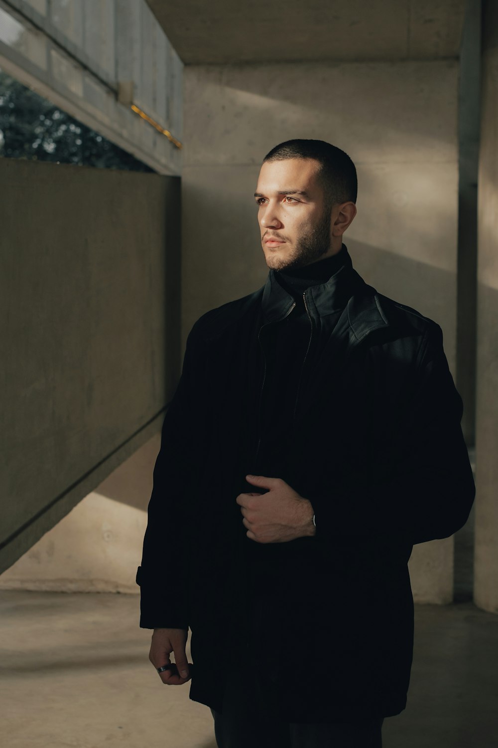 a man in a black coat standing in a building