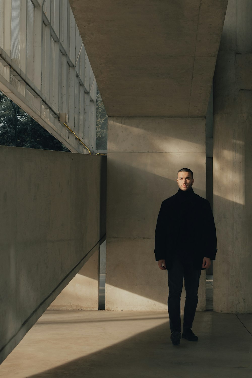 a man in a black coat standing in a hallway