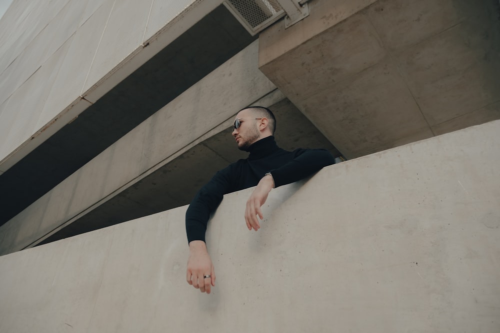 a man in a black shirt leaning against a wall