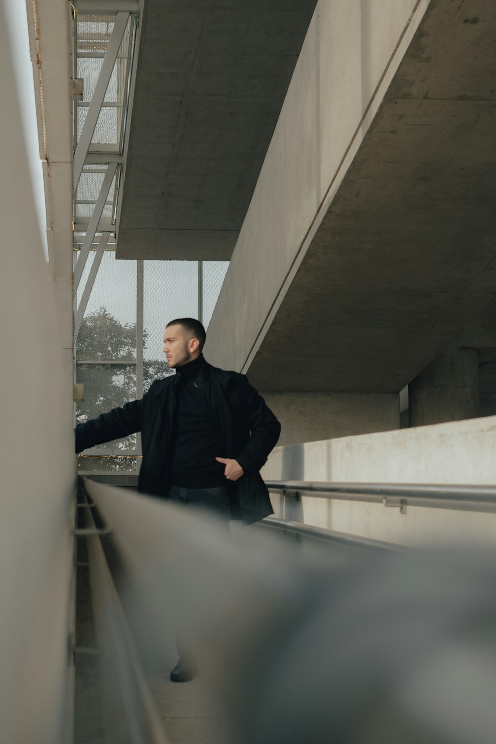 a man in a black coat leaning against a wall