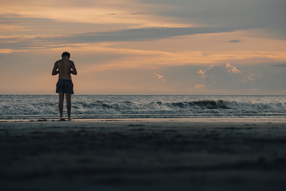 a man standing on top of a beach next to the ocean