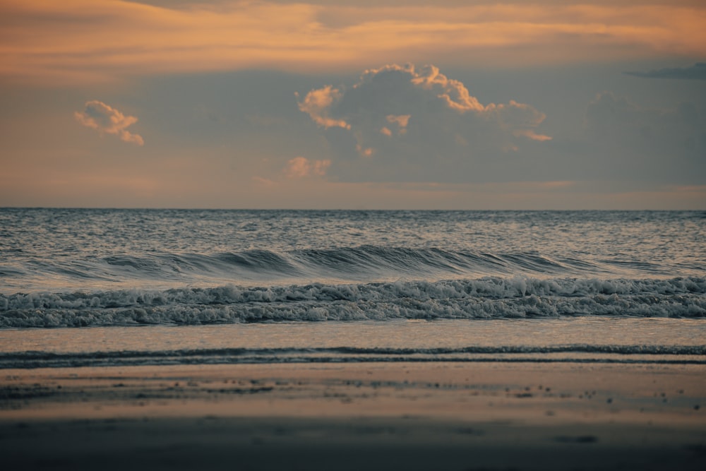 an ocean with waves and a cloud in the sky