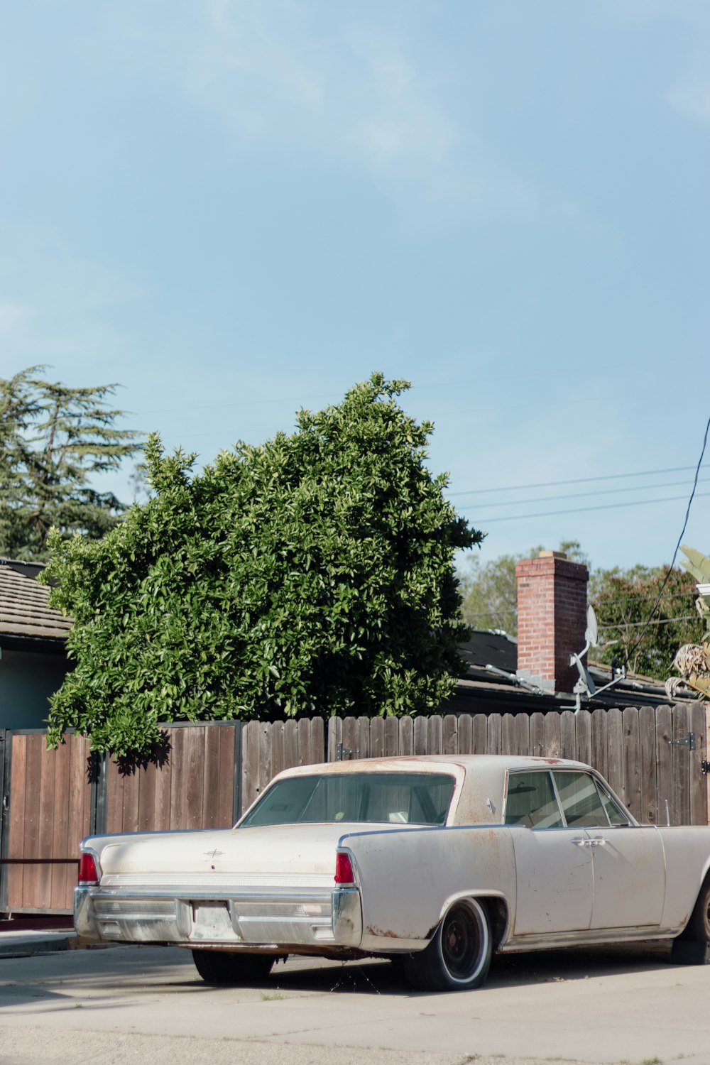 a white car parked in front of a wooden fence