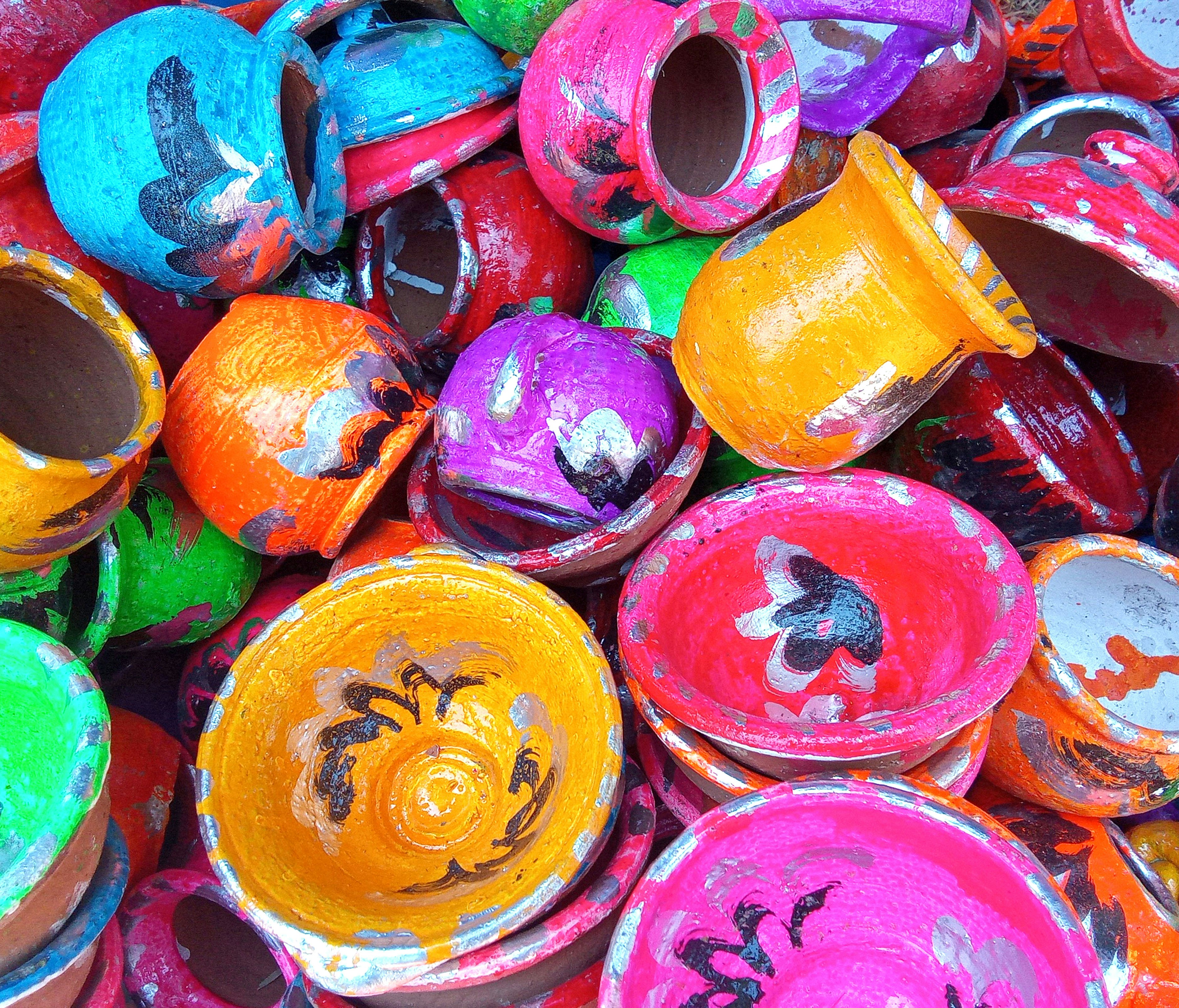 a pile of colorful painted pots sitting next to each other