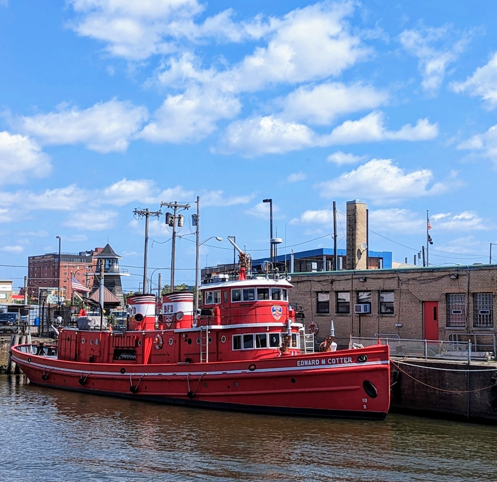 a red tug boat docked in a harbor