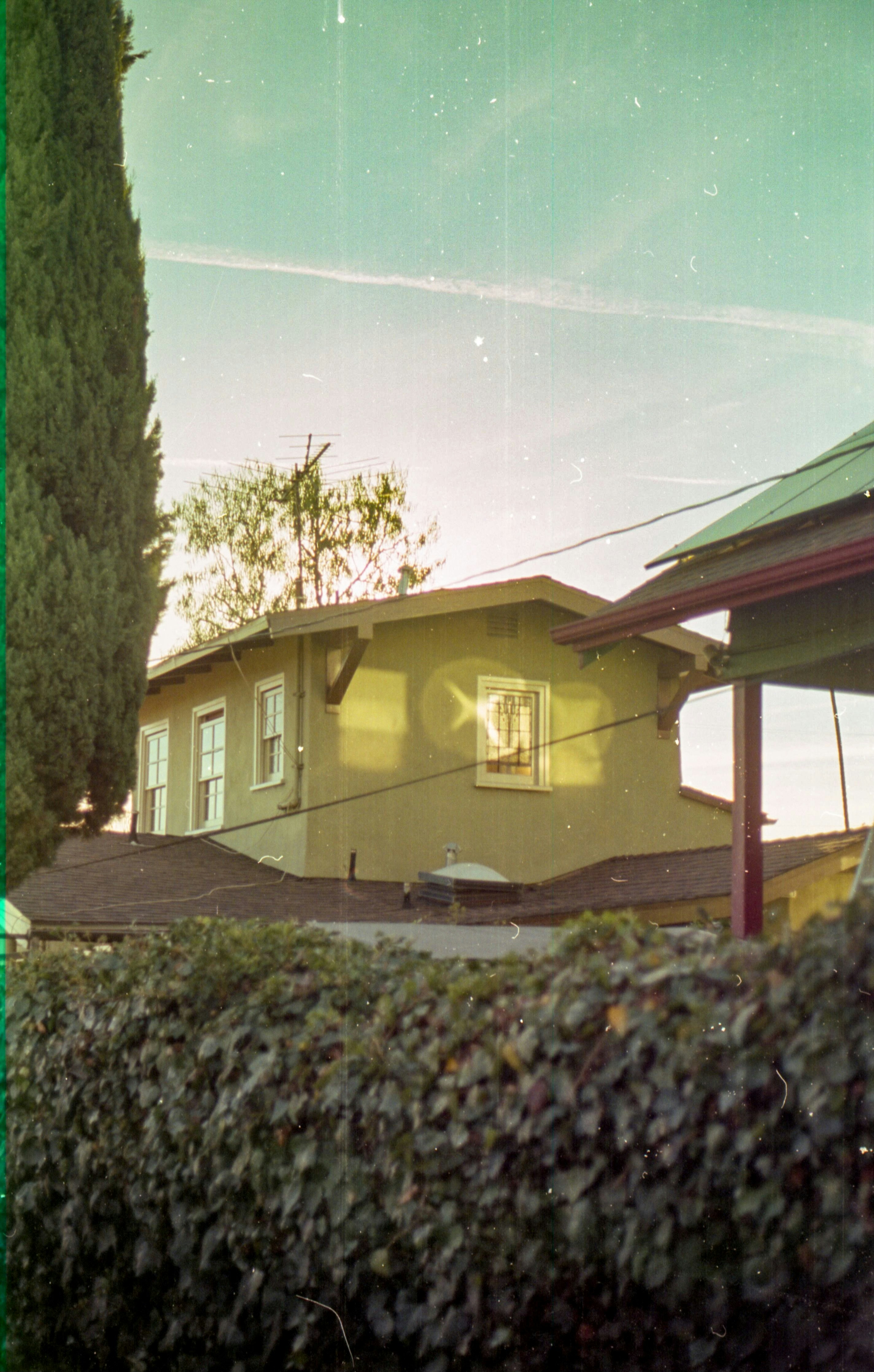una casa amarilla con un techo verde y un techo rojo