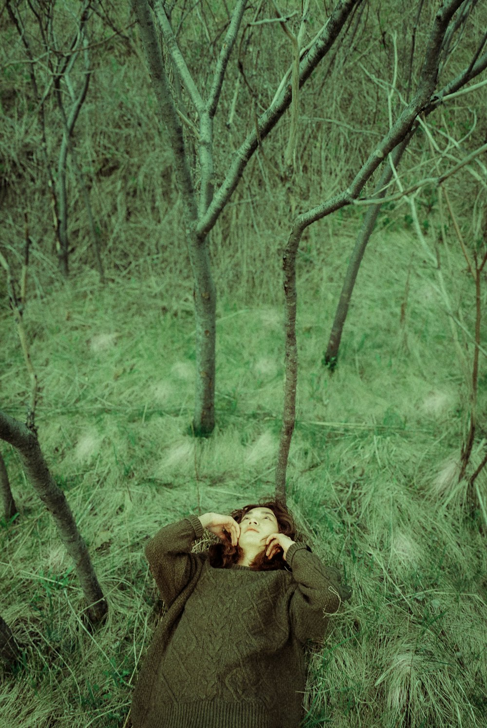 a woman laying in the grass with her head in a bag