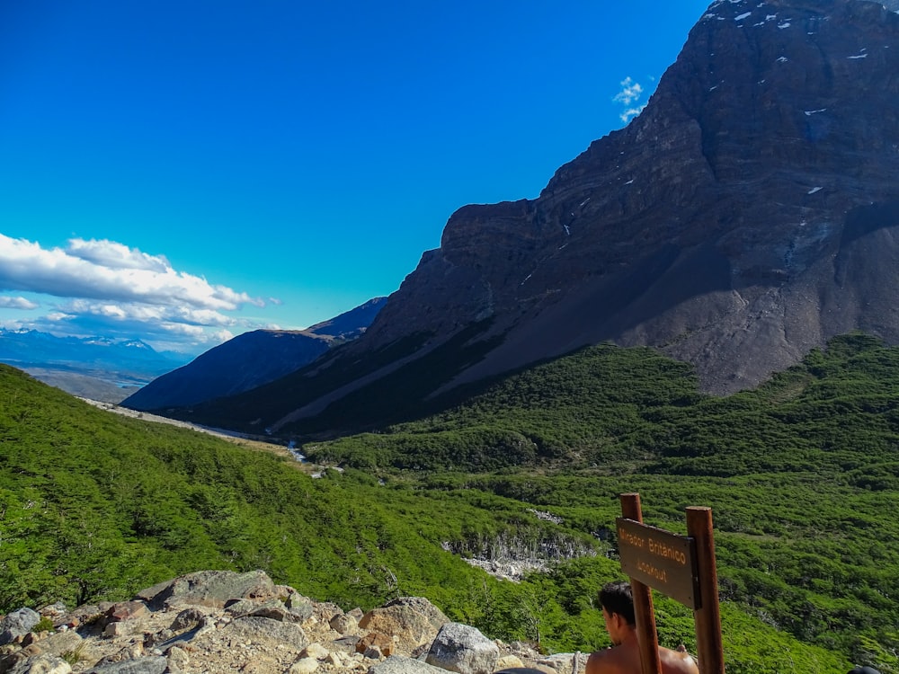 a man sitting on a bench looking at the mountains