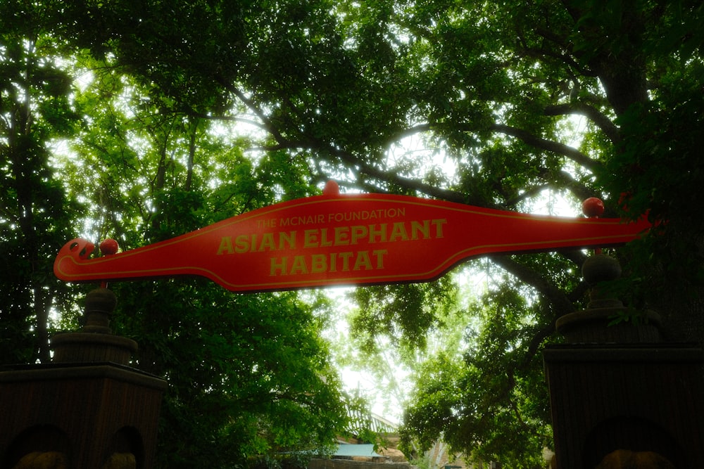 a red street sign hanging from the side of a lush green forest