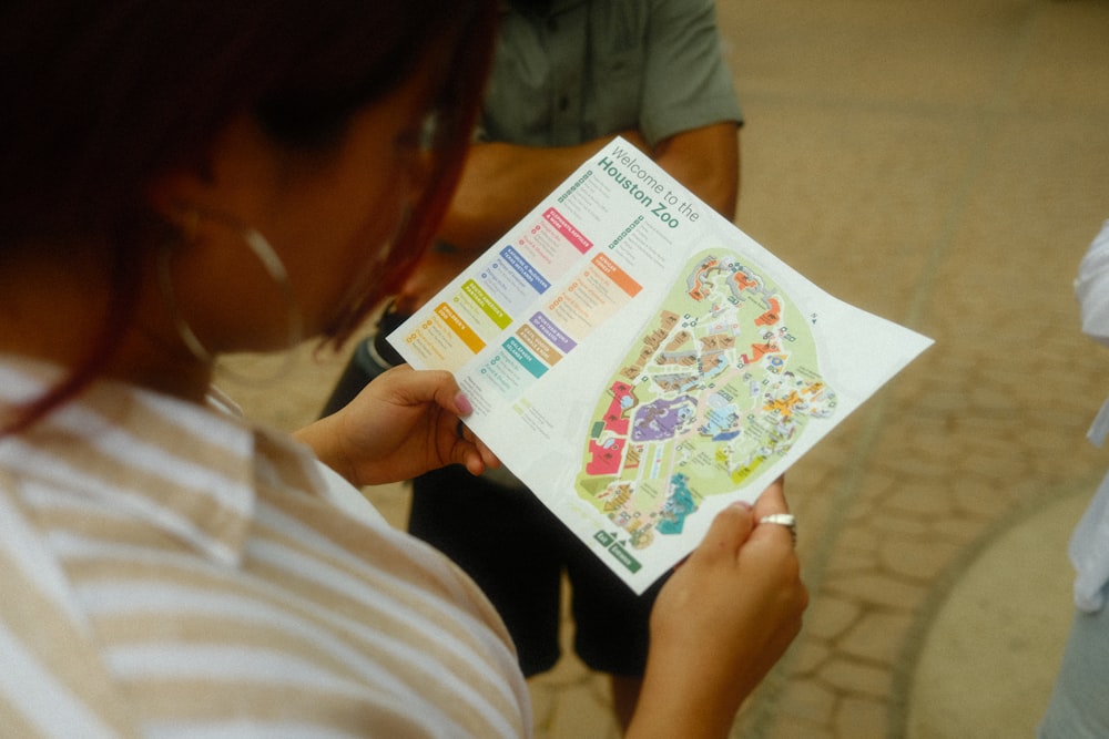 a woman holding a piece of paper with a map on it