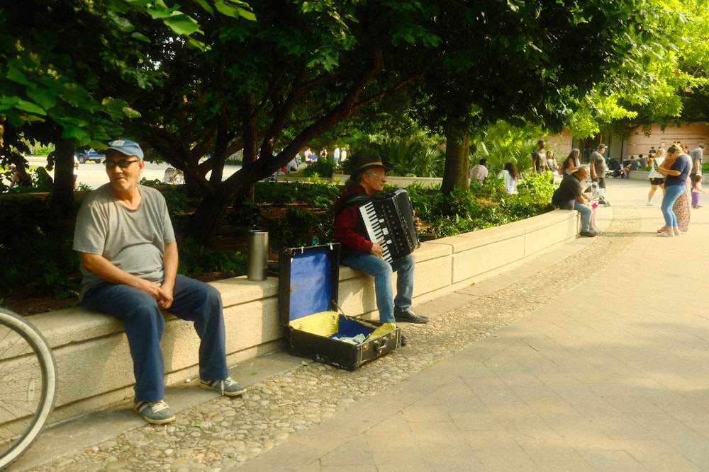 a man sitting on a wall next to a man playing an accordion