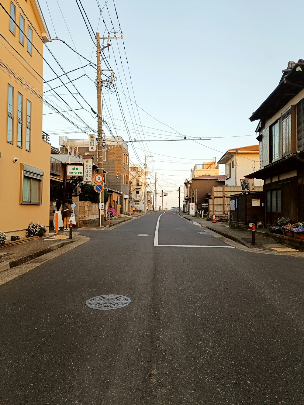 an empty street with houses and power lines in the background
