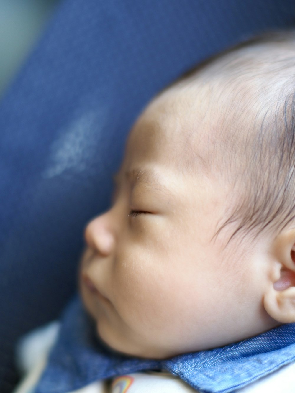 a close up of a baby sleeping on a blue blanket