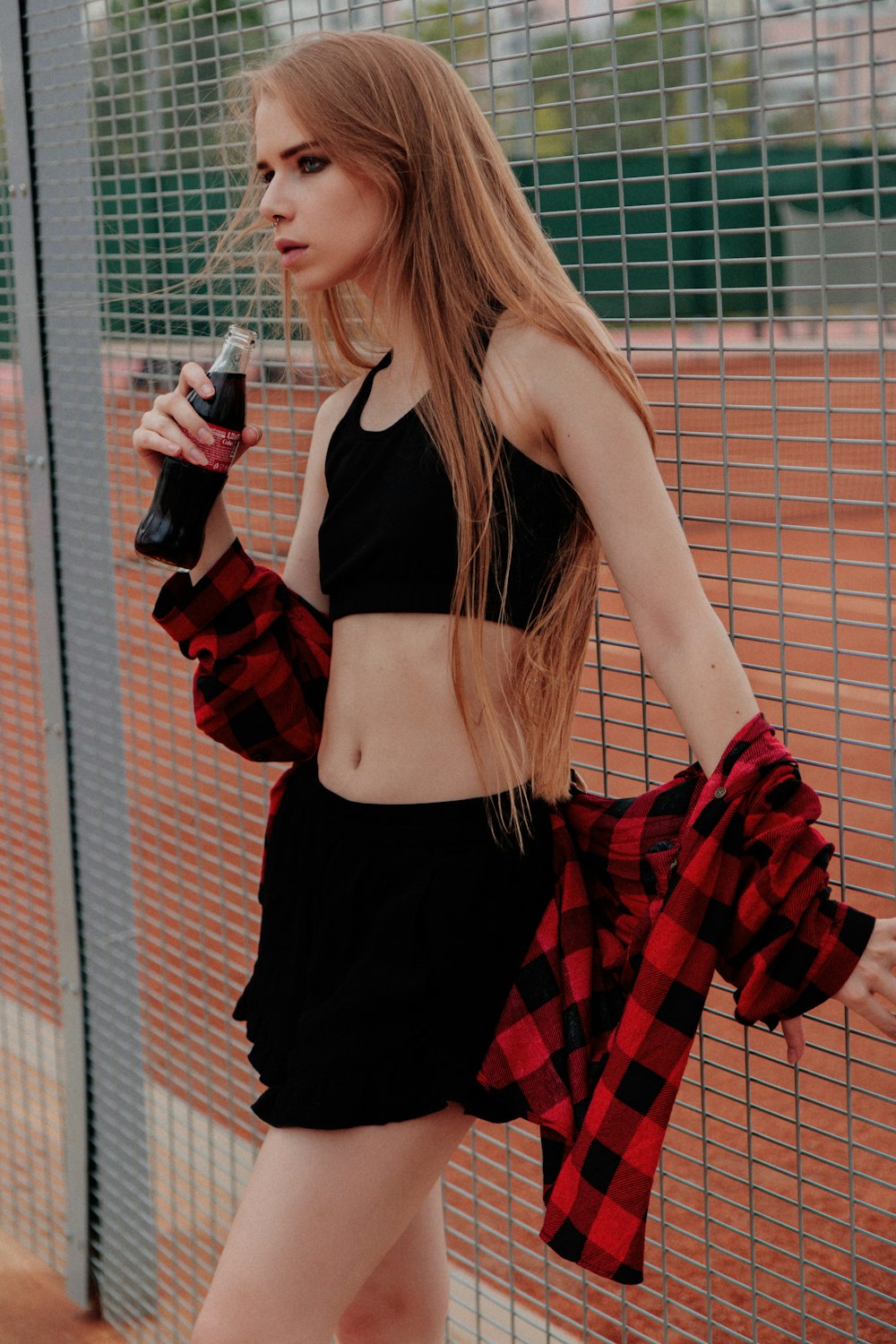 a woman in a black and red outfit holding a bottle