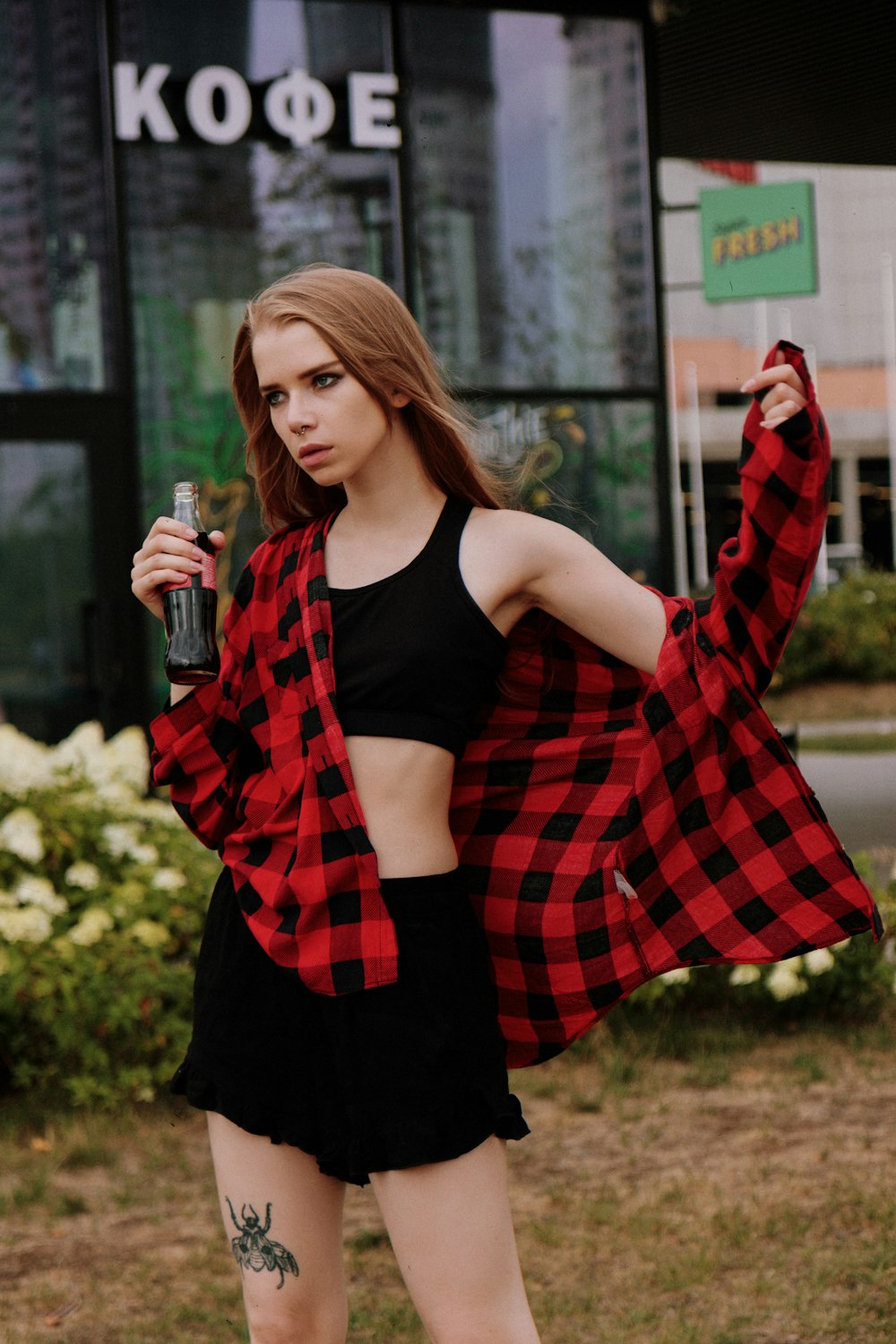 a woman in a red and black jacket holding a soda