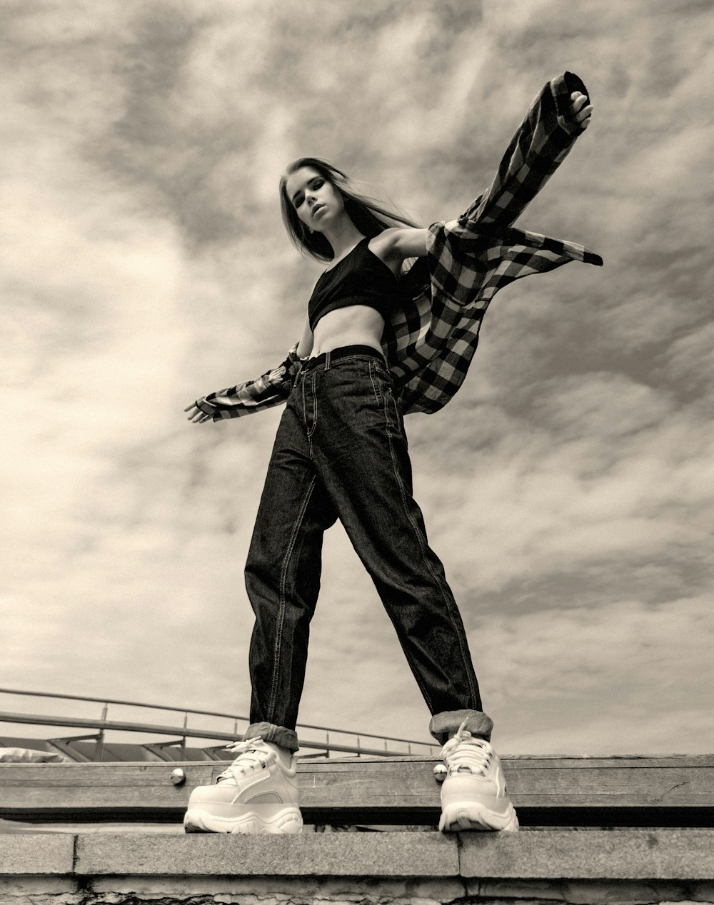 a woman standing on a ledge with her arms in the air