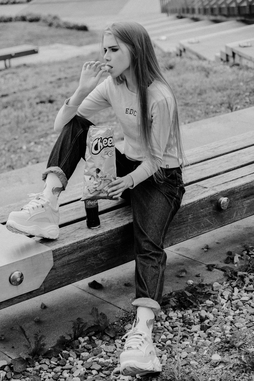 a girl sitting on a bench smoking a cigarette