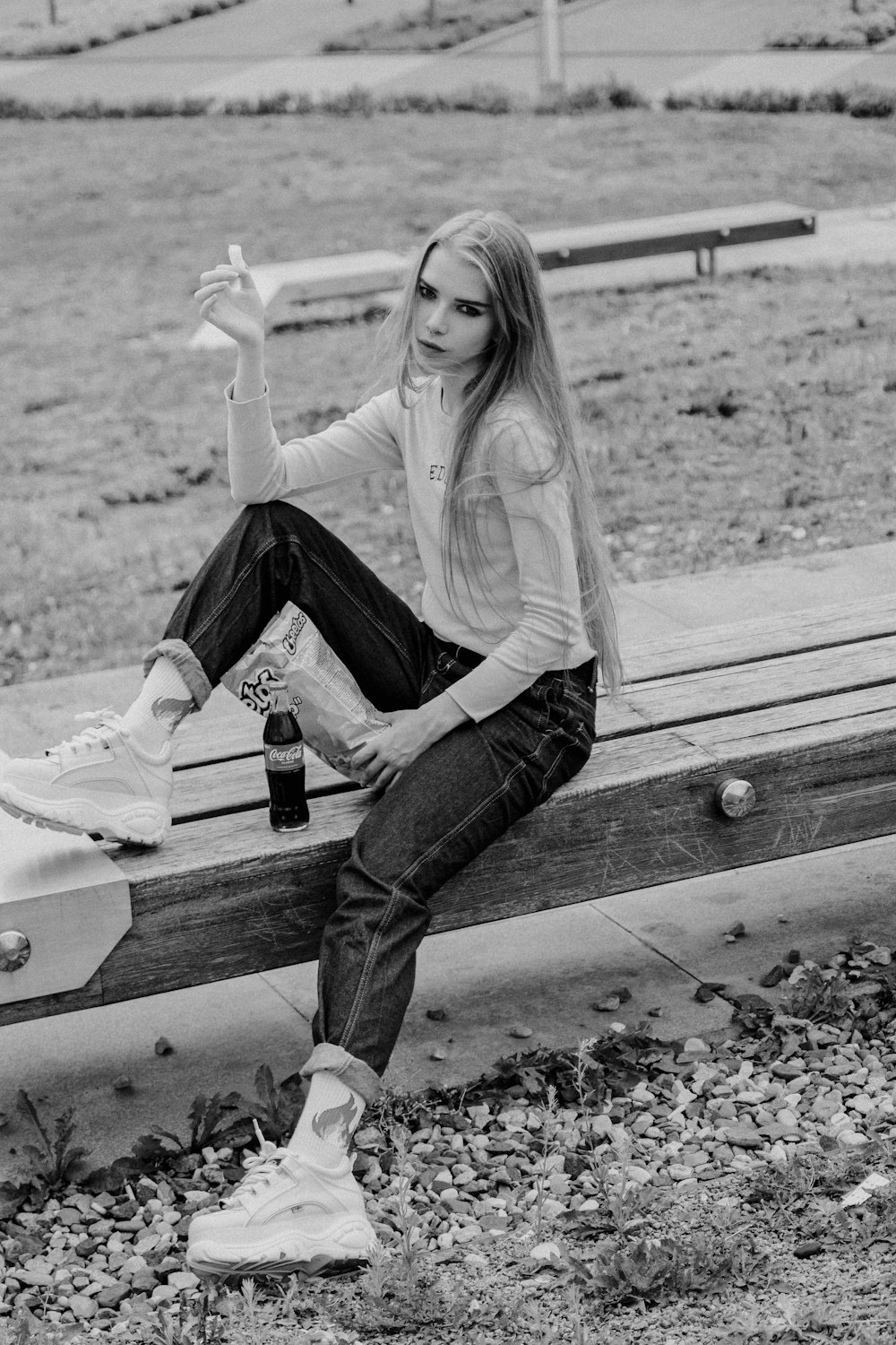 a woman sitting on a bench with a bottle of beer