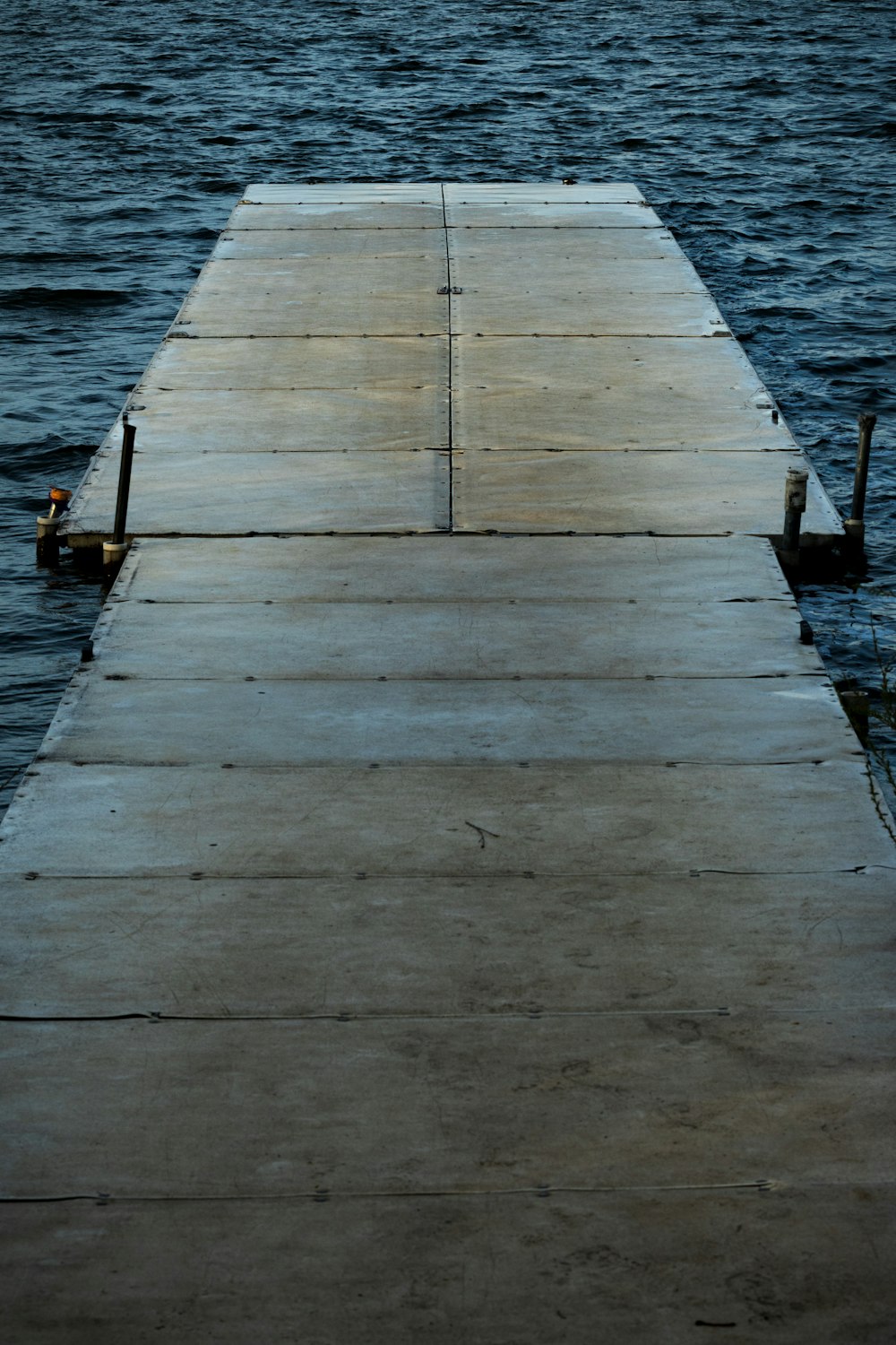 a dock with a bird sitting on the end of it