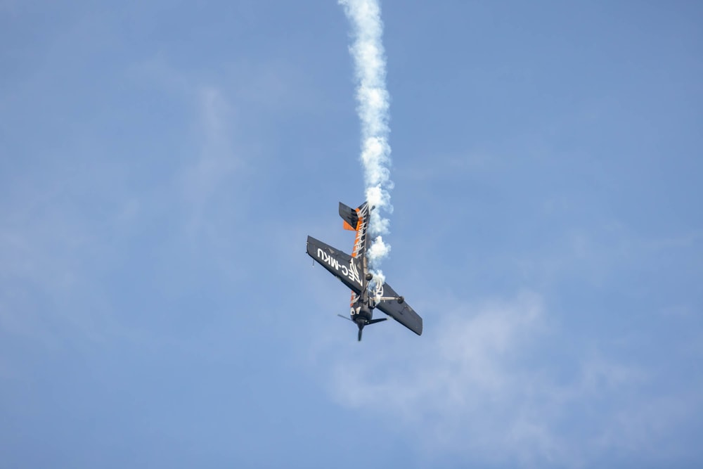 a small airplane flying through a blue sky