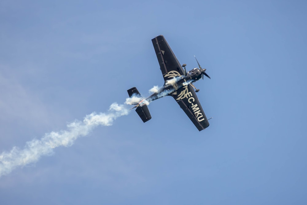 a small airplane flying through a blue sky