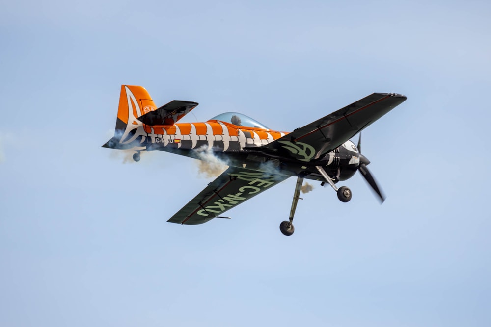 an orange and white plane flying in the sky