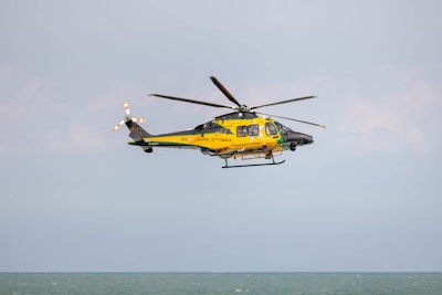a yellow and black helicopter flying over the ocean