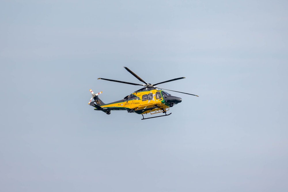 a yellow and black helicopter flying in the sky