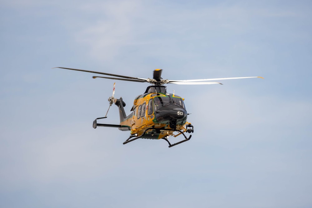 a yellow and black helicopter flying through a blue sky