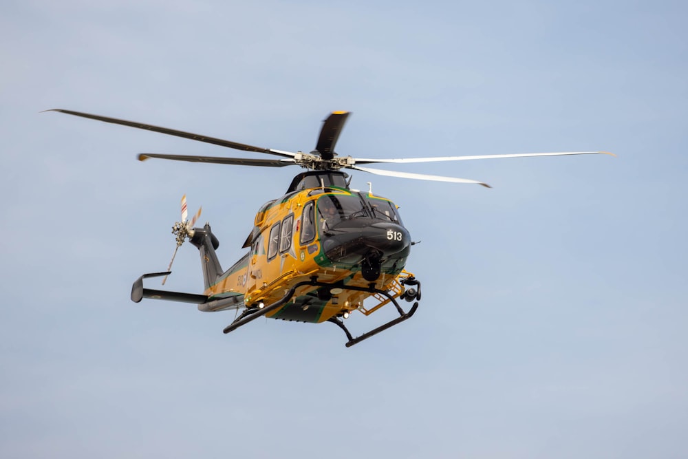 a yellow and black helicopter flying through a blue sky