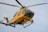 a yellow and green helicopter flying through a blue sky