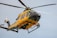 a yellow and green helicopter flying through a blue sky