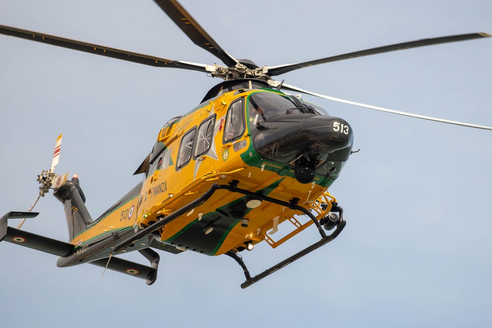 a yellow and green helicopter flying through a blue sky