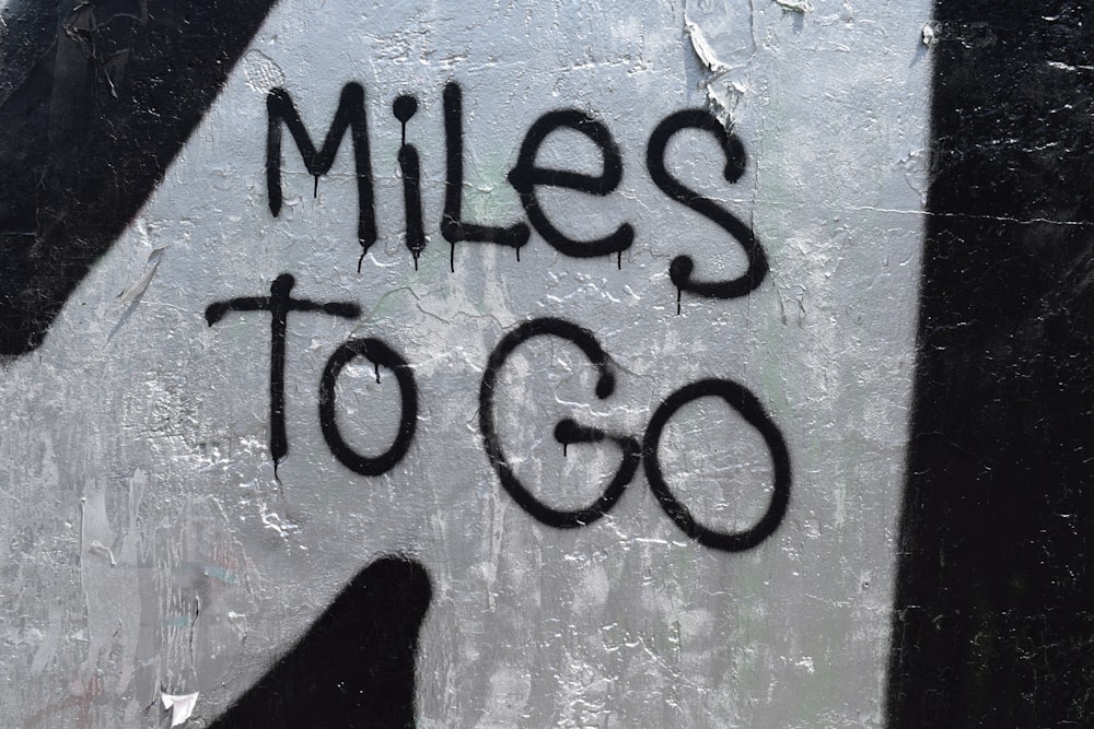 graffiti on the side of a building reads miles to go