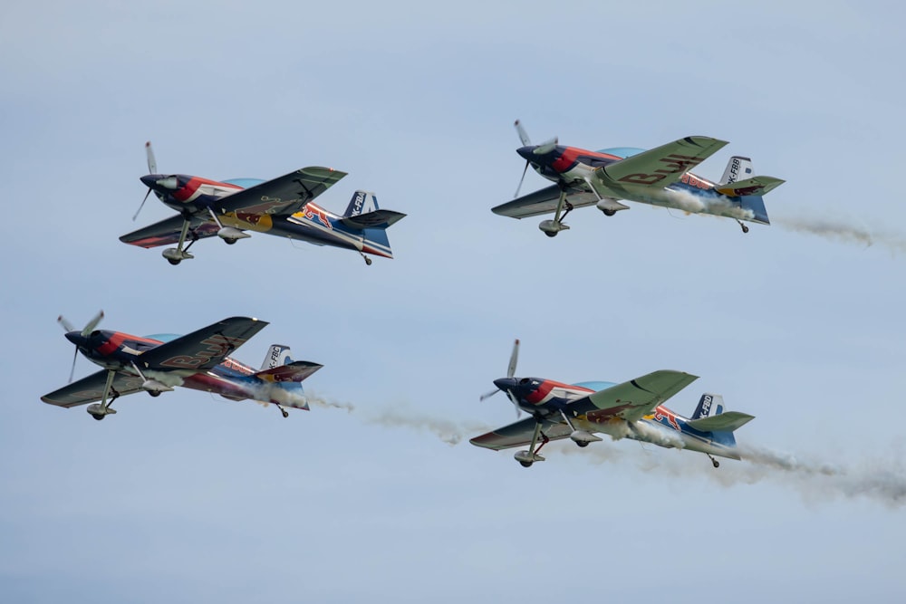 a group of four planes flying through a blue sky