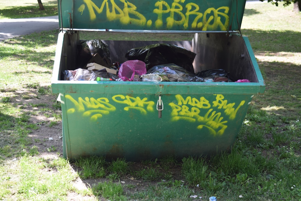 a green trash can with graffiti on it