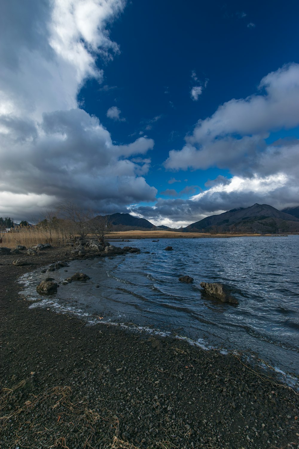 a body of water surrounded by mountains under a cloudy sky