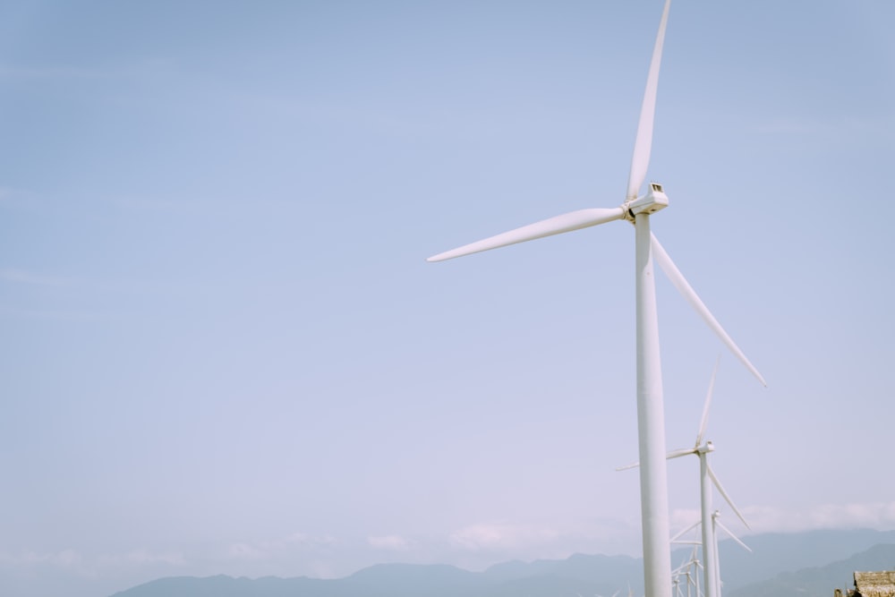 a group of windmills in a field with mountains in the background