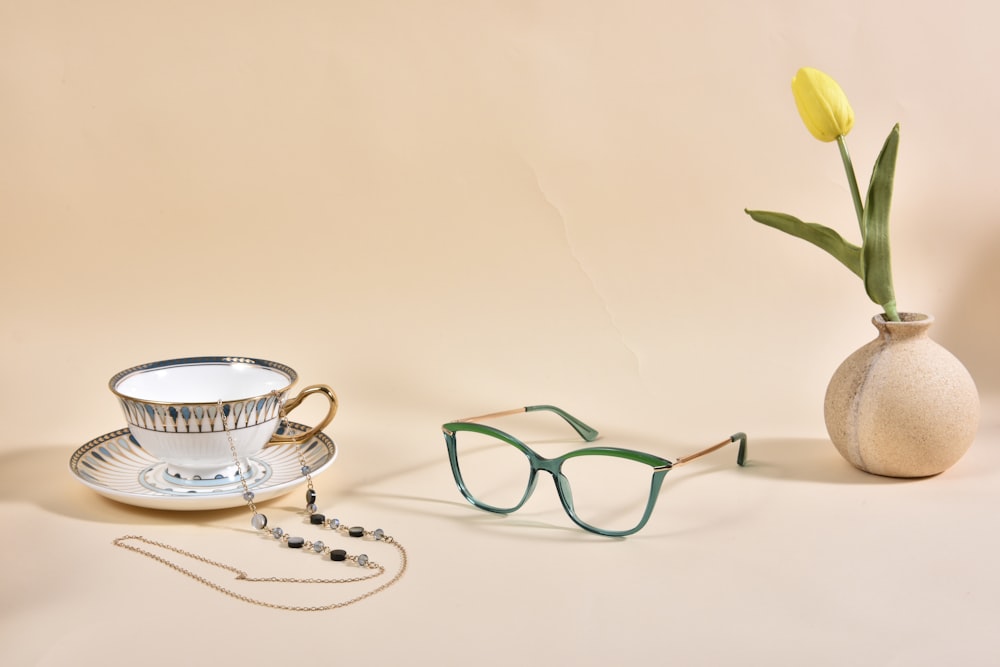 a vase with a flower and a pair of glasses